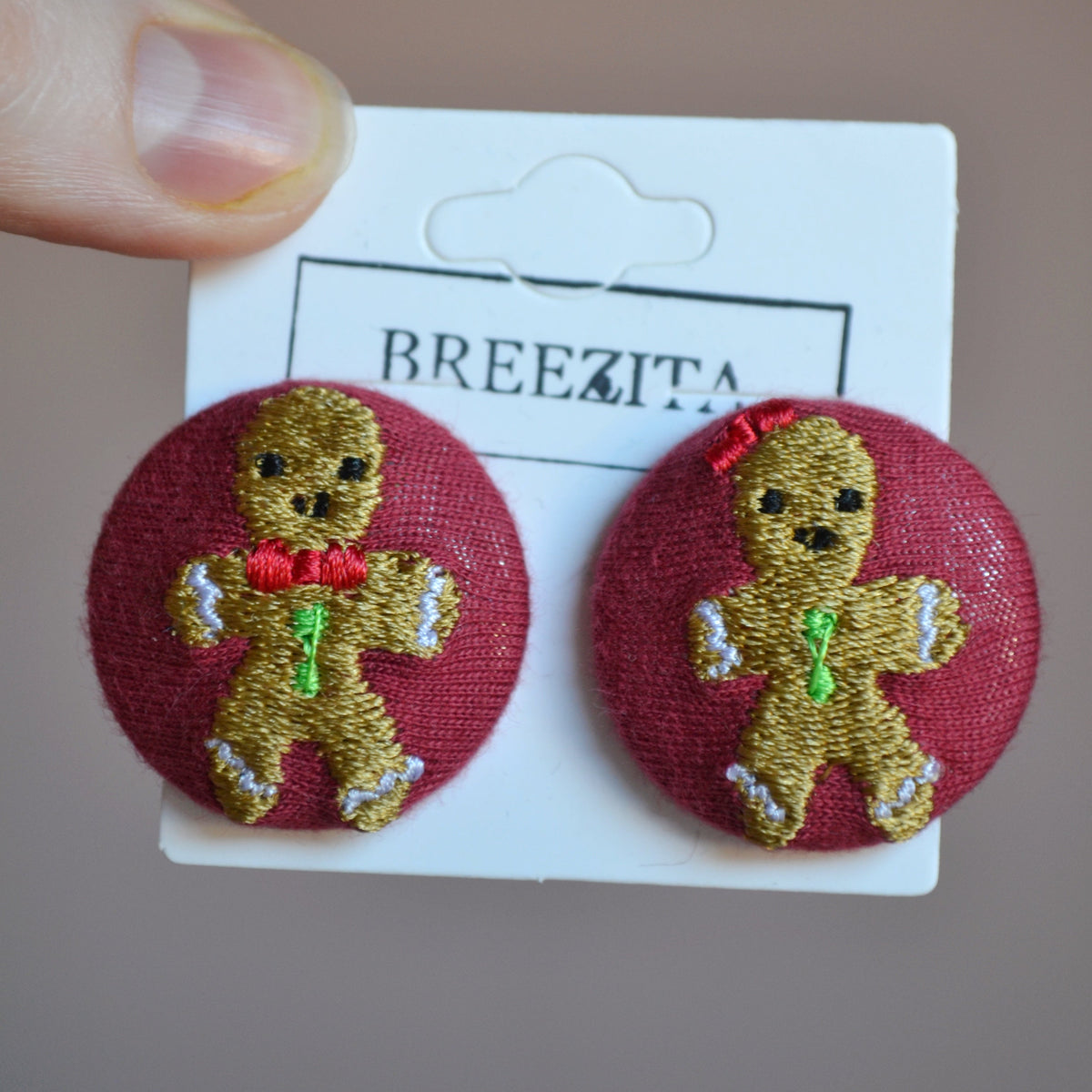 Pair of gingerbread man earrings on a Breezita card against a neutral background