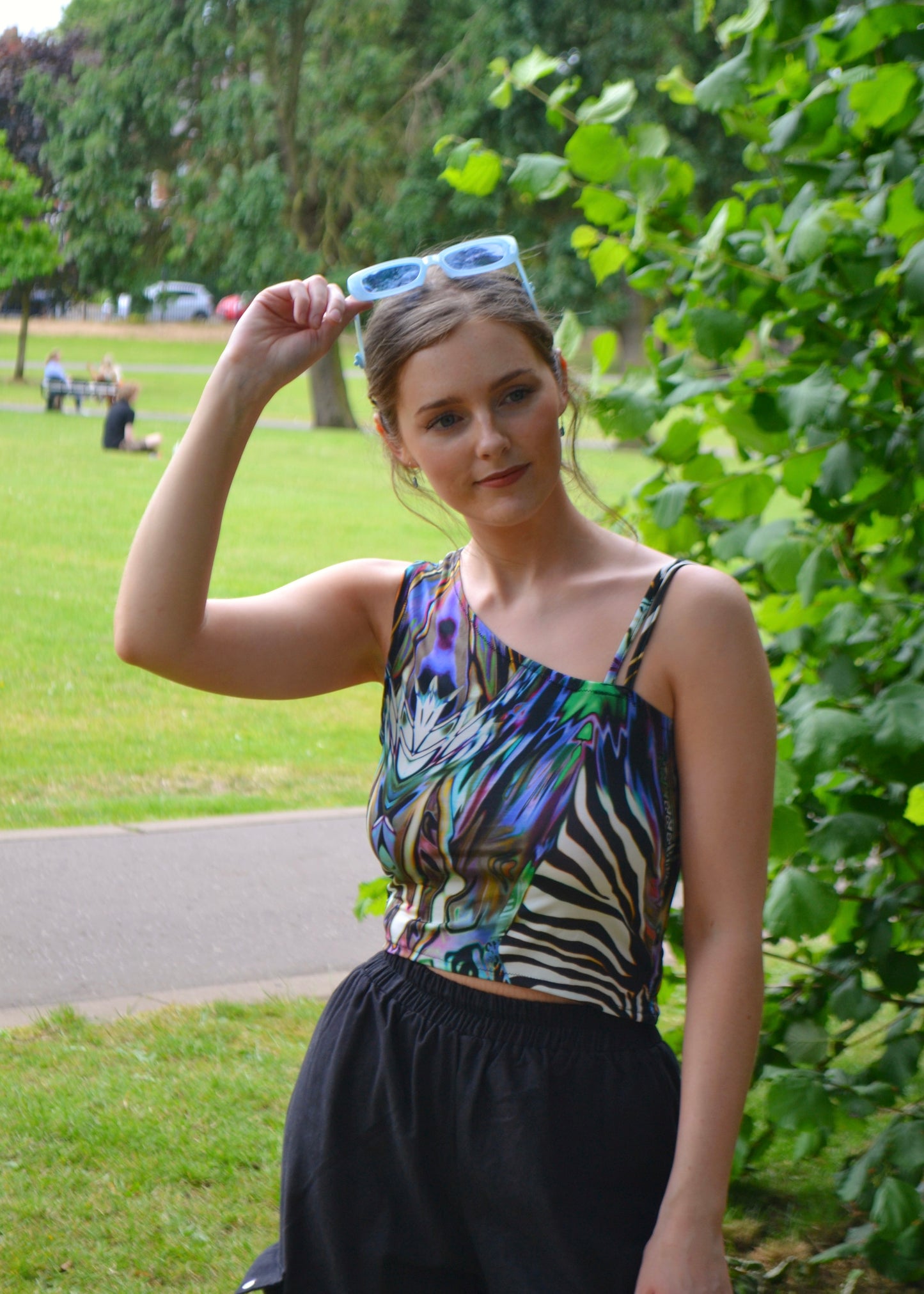 Close-up of model lifting sunglasses, vibrant animal prints on handmade festival top
