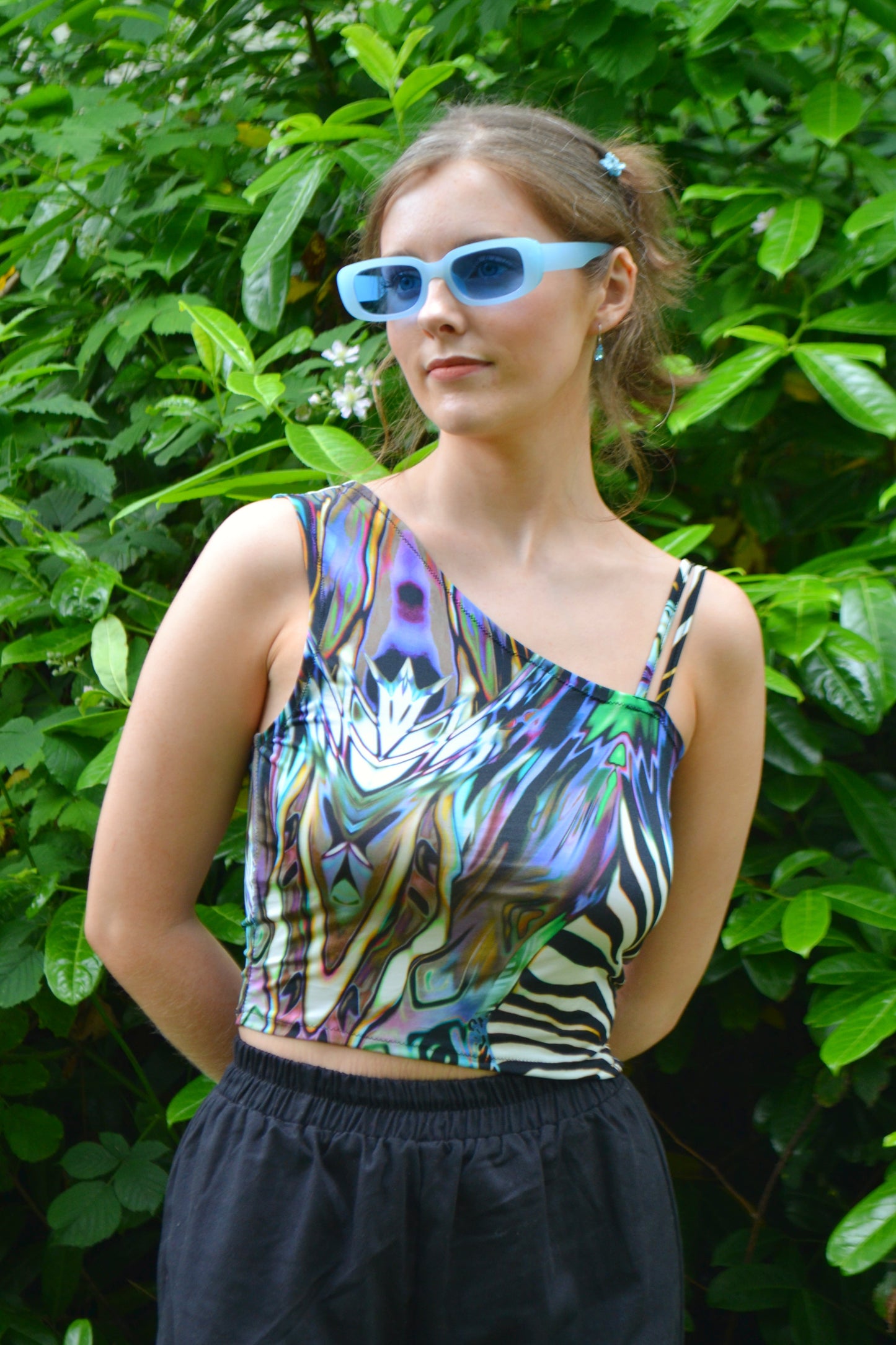 Front view of handmade one-shoulder animal-print top against lush green backdrop