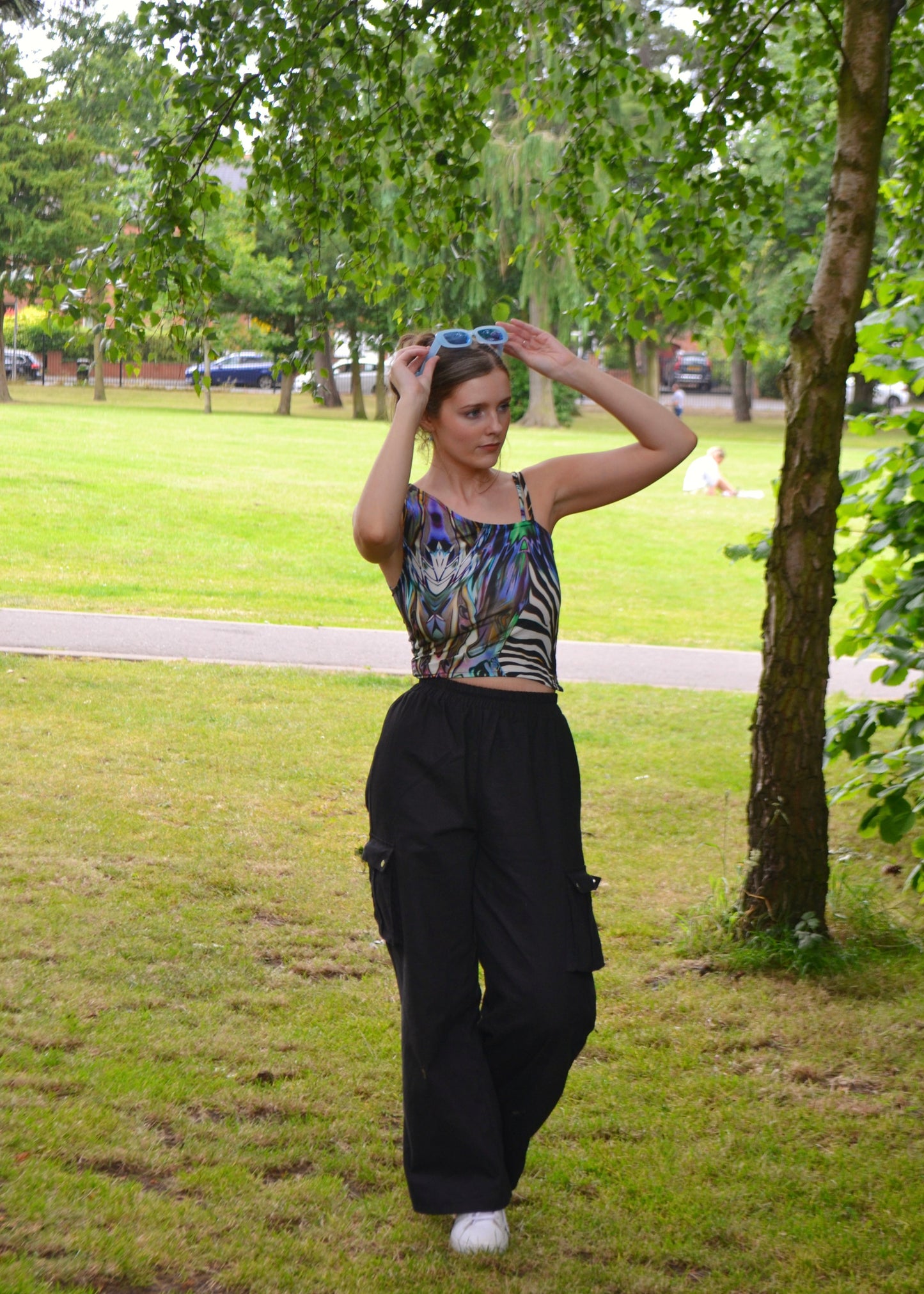 Model adjusting sunglasses, festival-ready outfit featuring handmade animal-print top