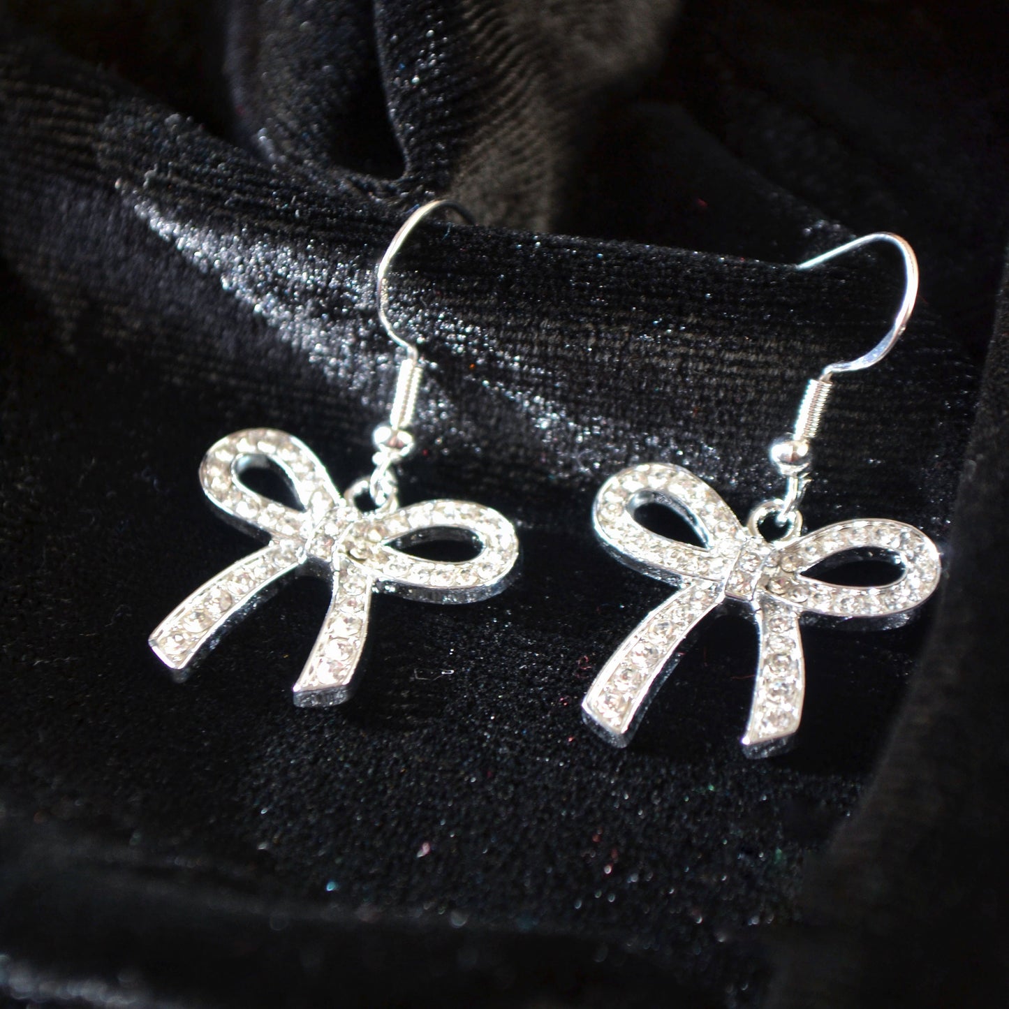 Silver bow-shaped earrings on a black background