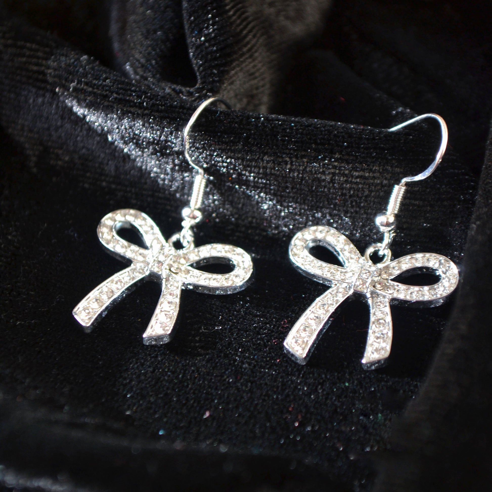 Silver bow-shaped earrings on a black background