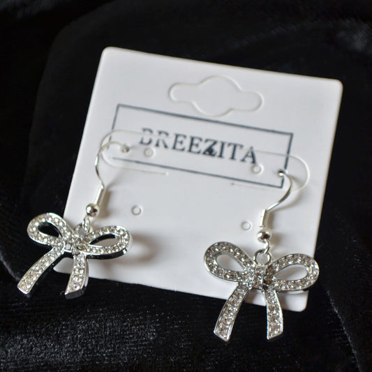 Bow-shaped earrings on a Breezita branded card against a dark background
