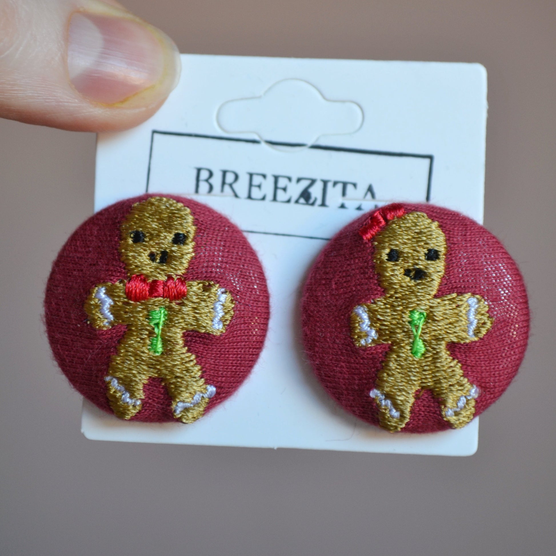 Pair of gingerbread man earrings on a Breezita card against a neutral background