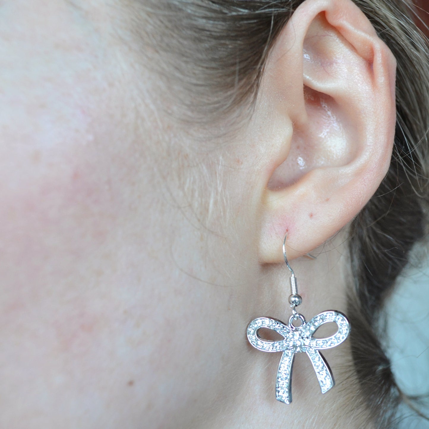 Close-up of an ear wearing a bow-shaped earring.