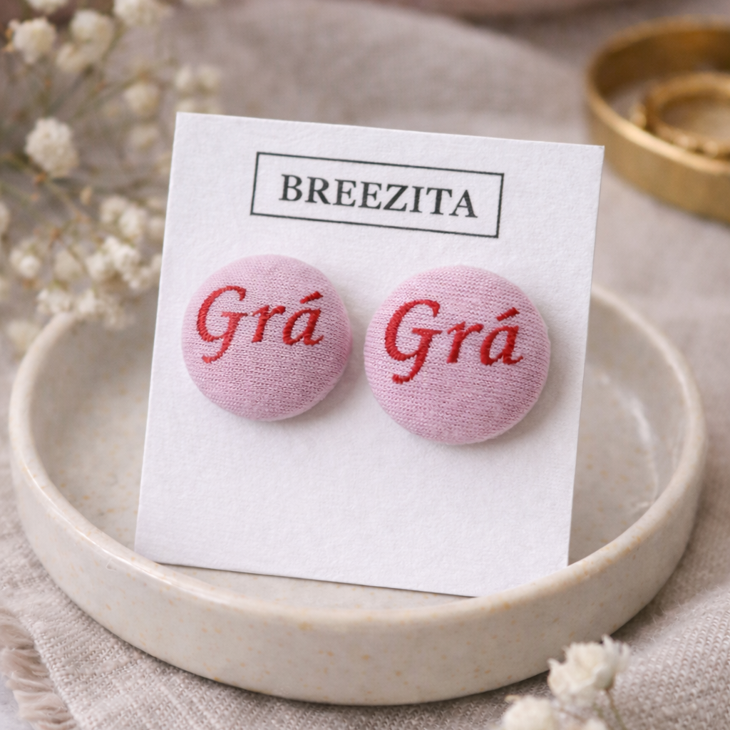 Pink earrings with 'Grá' text on a BREEZITA branded card, displayed on a beige plate.