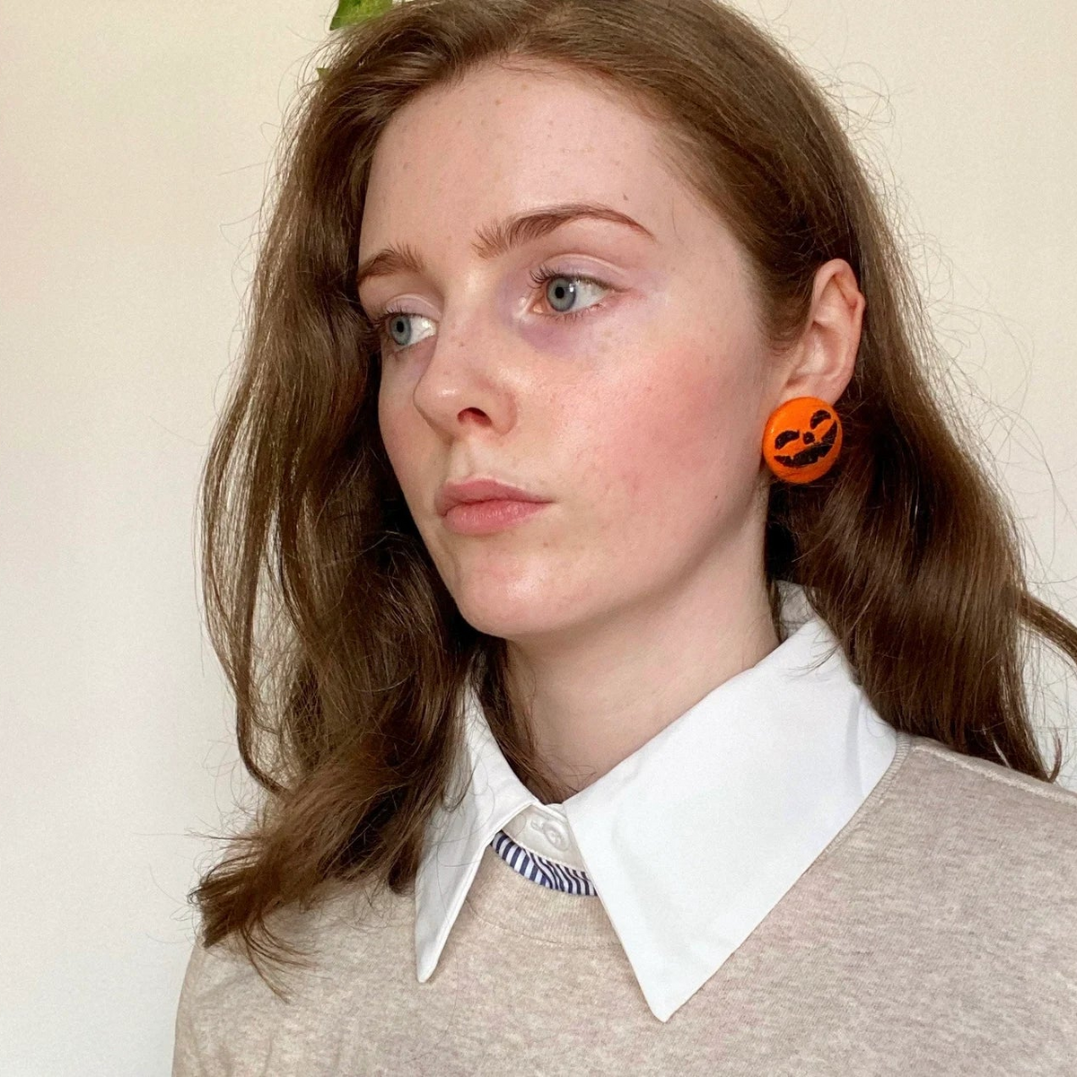 Model wearing spooky embroidered pumpkin face earrings, perfect handmade Halloween statement jewelry.